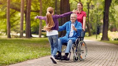 cheerful disabled grandfather in wheelchair welcoming his happy granddaughter