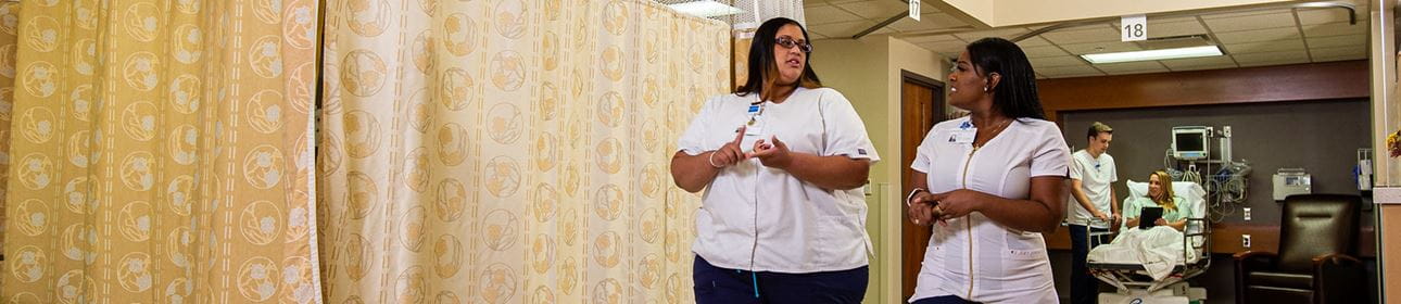Practical Nurses talking as they help a patient