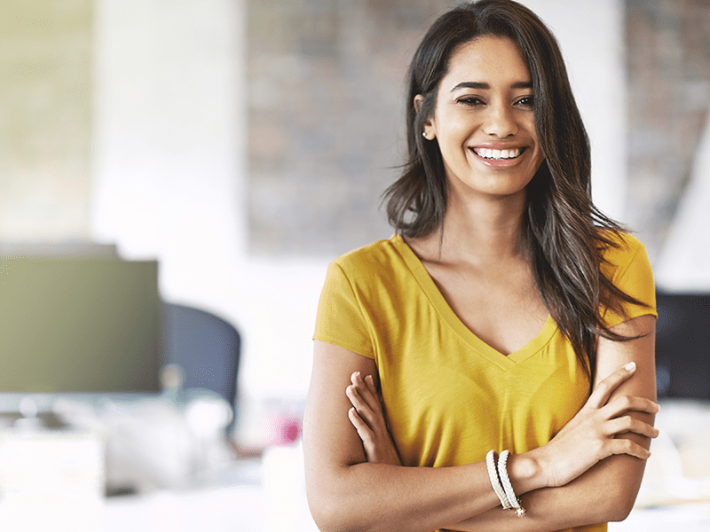 woman in yellow shirt smiling with her hands folded